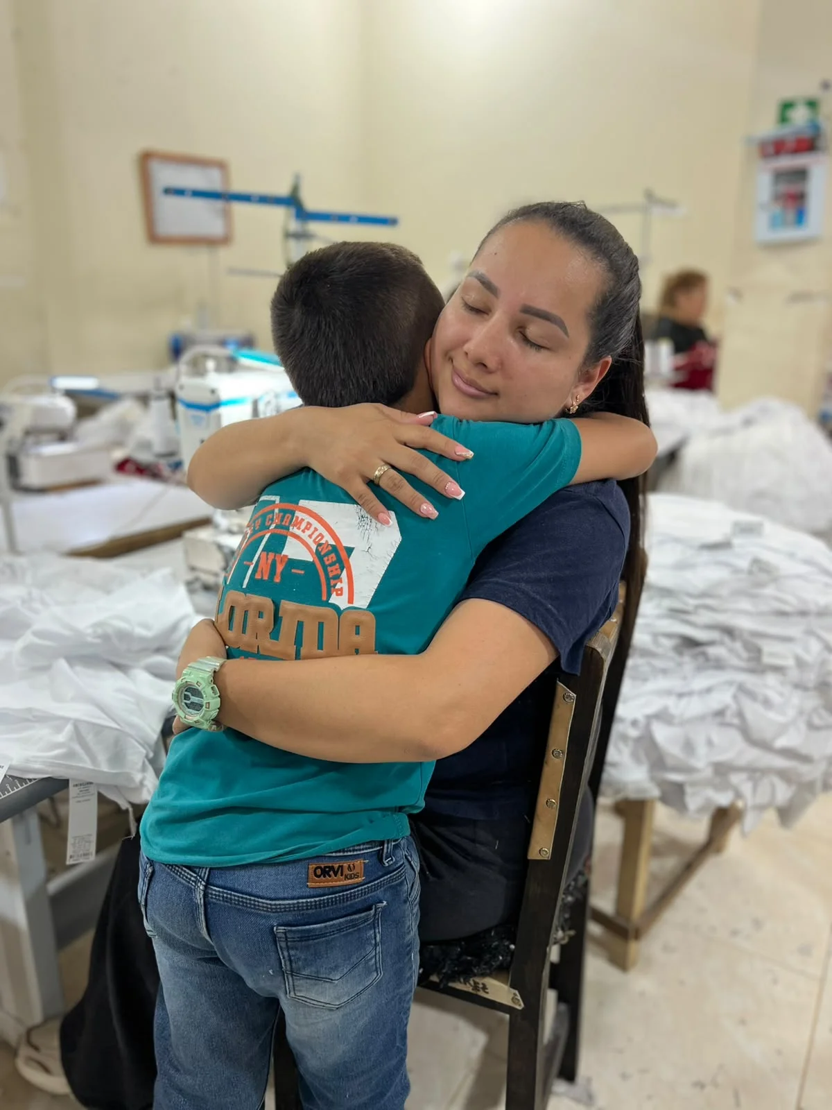 Marlen Quiñones Cano, fundadora de MAINTEGRAL CONFECCIONES, en un emotivo abrazo en el taller de confección en Medellín tras recibir el reconocimiento FamiEmpresario Interactuar 2026